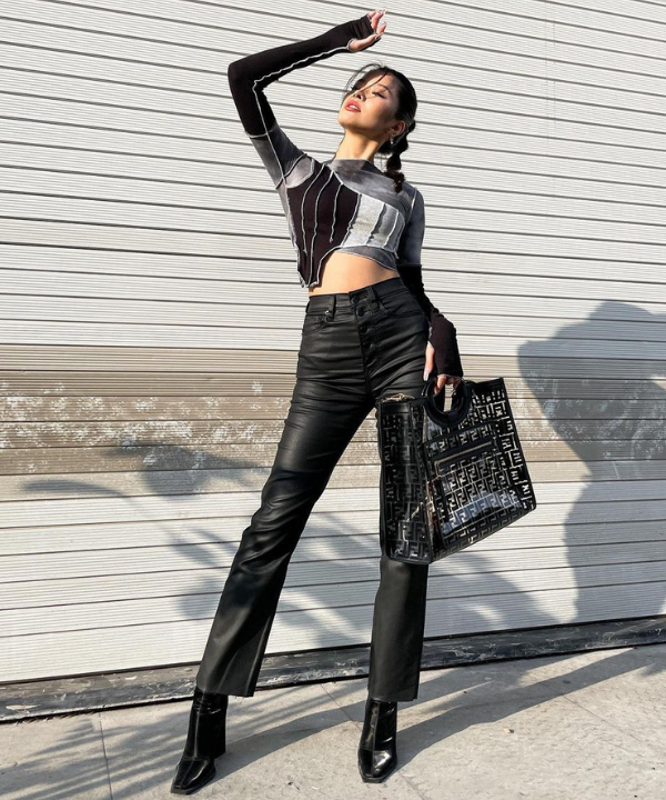 Caroline Hu - blusa estampada com calça preta e bota - looks em dias chuvosos - Primavera - no sol em frente a uma porta - https://stealthelook.com.br