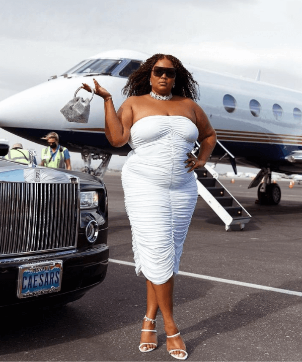 Lizzo - vestido drapeado branco - looks de festa - Verão - parada em frente a um avião - https://stealthelook.com.br