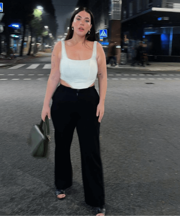 Cassandra Klatzkow - calça preta, corset branco e sandálias - looks novos - verão - em pé na rua - https://stealthelook.com.br