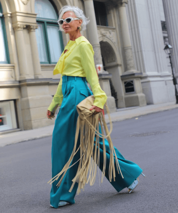 Grece Ghanem - calças azuis, blusa verde e bolsa de franjas amarela - tendência dos anos 70 - verão - andando na rua - https://stealthelook.com.br