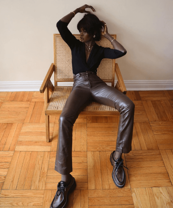 Amy Julliette Lefévre - calça de p.u marrom e blusa preta - calça tendência - Outono - sentada em uma cadeira - https://stealthelook.com.br