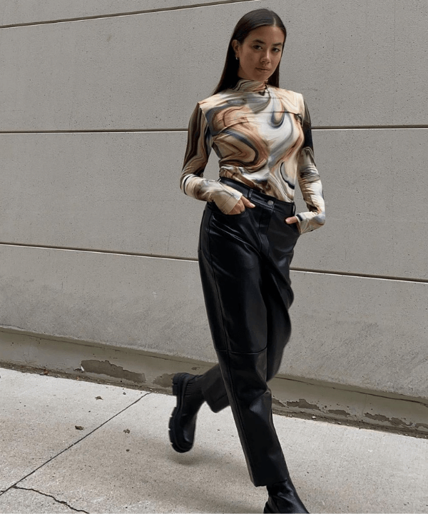 Sasha Mei - calça de P.U preta e blusa com estampa psicodélica - tendências de moda - Inverno - em pé na rua - https://stealthelook.com.br
