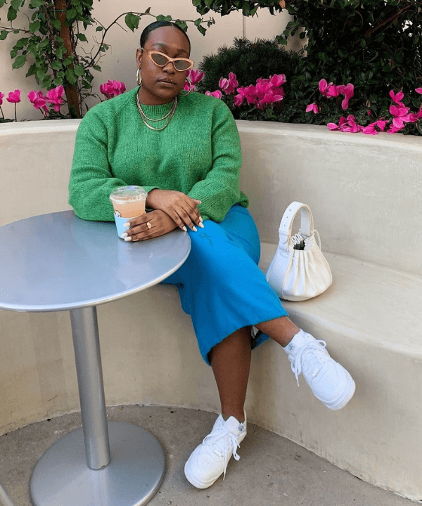 Aniyah Morinia - saia azul, tricot verde e tênis branco - sapatos que nunca saem de moda - verão - sentada em uma cadeira - https://stealthelook.com.br