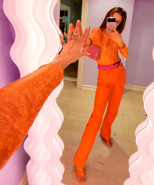 Nina Sandbech - blusa e calça laranja com cinto e bolsa rosa - looks coloridos - Verão 2022 - foto no espelho - https://stealthelook.com.br