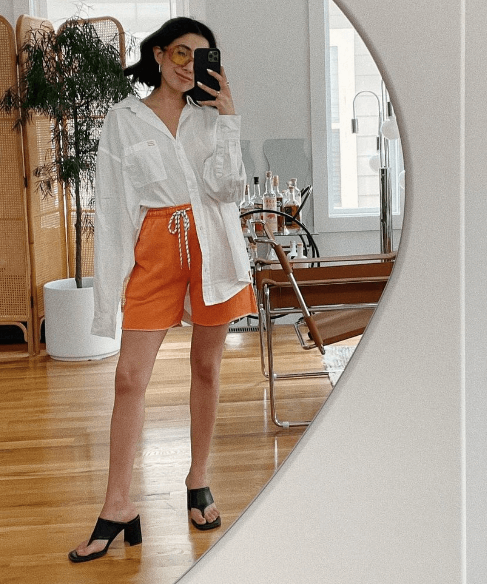@aprillockhart - shorts laranja e camisa oversized branca - looks novos - Verão - foto na frente do espelho - https://stealthelook.com.br