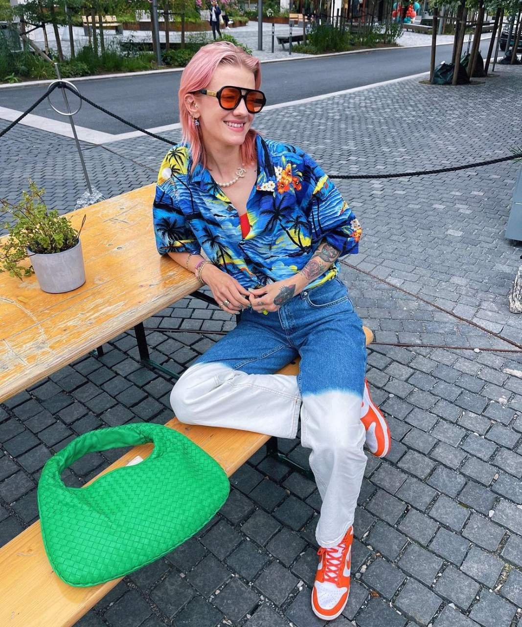 Marianne Theodorsen - camisa estampada com jeans e tênis - looks com camisa estampada - Verão 2022 - sentada no banco - https://stealthelook.com.br