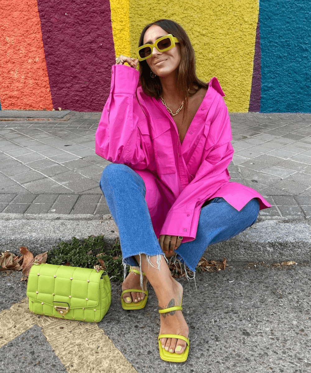 Laura Eguizabal - calça jeans, camisa rosa oversized e tamanco verde - looks básicos - verão - sentada na rua - https://stealthelook.com.br
