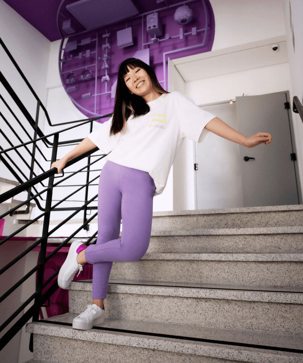 Milena Otta - camiseta branca com legging lilás e tênis - looks confortáveis - Verão 2022 - foto na escada - https://stealthelook.com.br