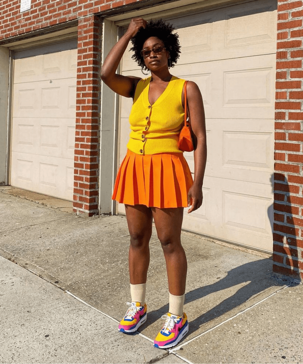 Yolande Macon - colete amarelo com saia college laranja e tênis jogging - sapatos estilosos - Verão 2022 - no sol - https://stealthelook.com.br