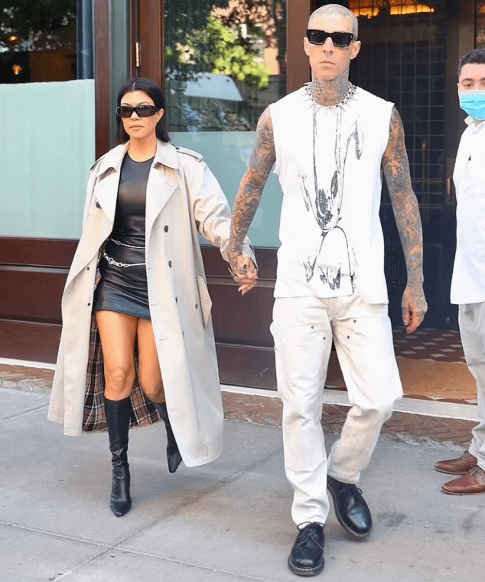 Kourtney Kardashian e Travis Barker - vestido curto preto, botas e trench coat - Valentine's Day - Outono - andando na rua - https://stealthelook.com.br