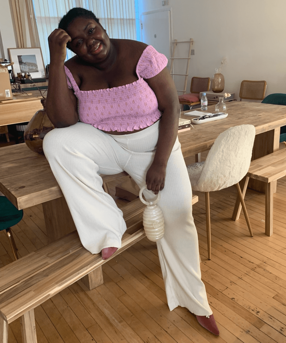 Abisola Omole - calça de malha de tricot e cropped de lastex rosa - looks com cropped - verão - sentada em uma cadeira - https://stealthelook.com.br