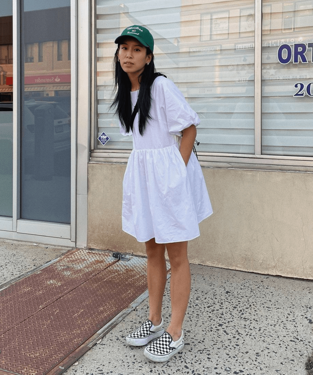 Kristen Lam - vestido curto branco de mangas bufantes, tênis quadriculado e boné verde - looks novos - Primavera - em pé na rua - https://stealthelook.com.br