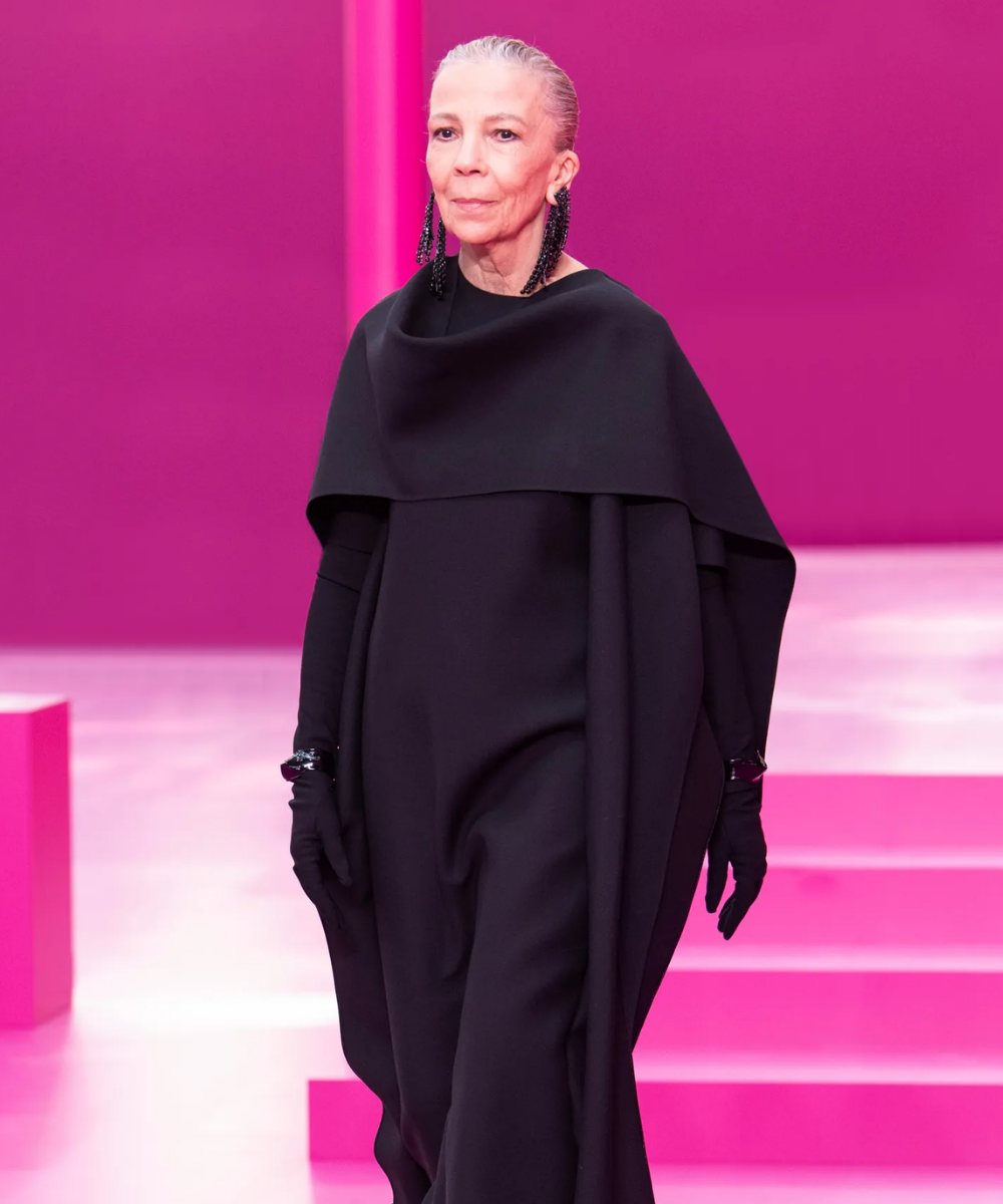Desfile Valentino - look todo preto com botas de plataforma - diversidade nas passarelas - Outono - modelo mais velha desfilando em uma passarela rosa - https://stealthelook.com.br