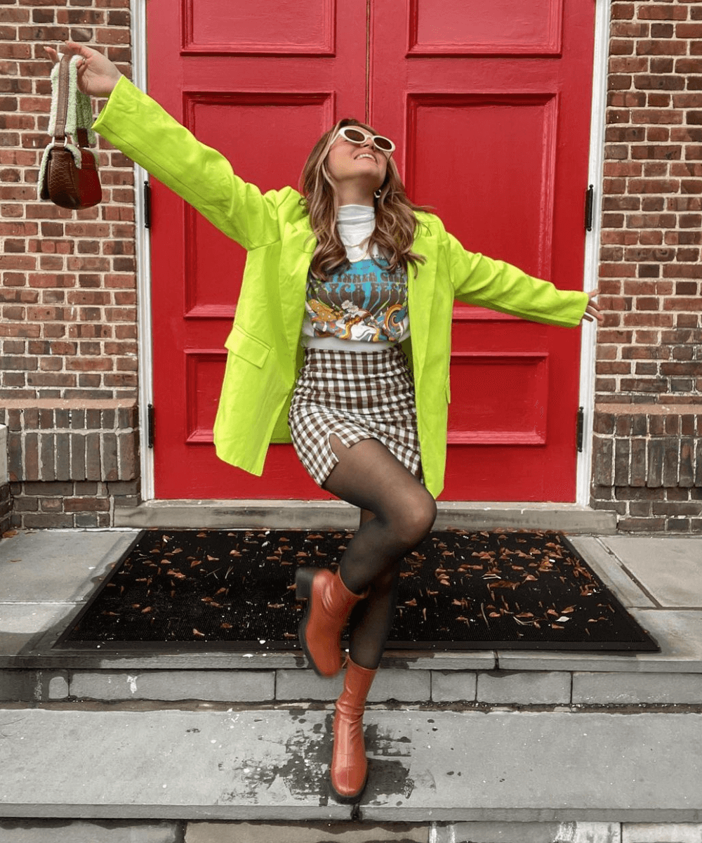 Amber Nicole - t-shirt estampada com blazer amarelo neon e saia com estampa vichy e bota - estampa vichy - Verão 2022 - em frente a uma escada - https://stealthelook.com.br