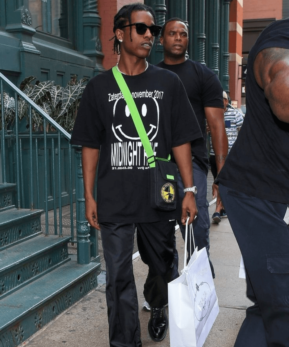 A$AP Rocky - calça preta, t-shirt preta e bolsa crossbody verde - Lollapalooza 2022 - Verão - andando na rua - https://stealthelook.com.br