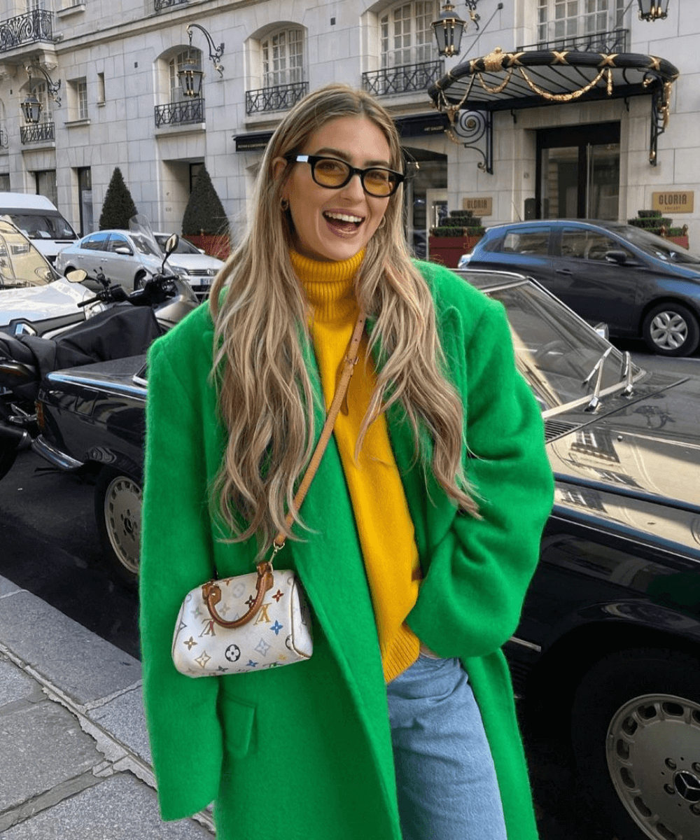 Emili Sindlev - calça jeans, blusa amarela e casaco verde longo - dopamine dressing - Inverno  - em pé na rua - https://stealthelook.com.br