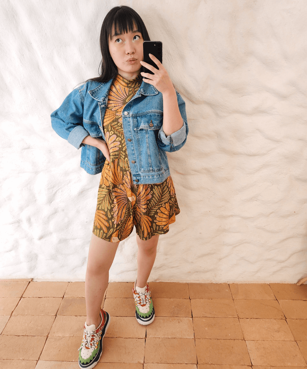 Milena Otta - vestido curto floral, jaqueta jeans e tênis - roupas estampadas - verão - foto na frente do espelho - https://stealthelook.com.br