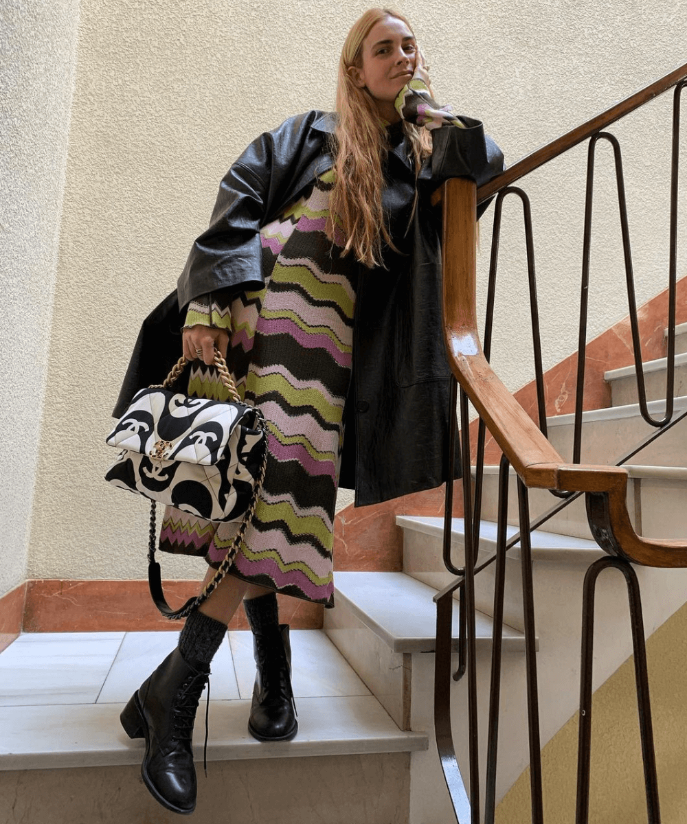 Blanca Miró Scrimieri - vestido listrado, casaco preto e botas - vestido no inverno - Inverno  - em pé em uma escada com as pernas cruzadas - https://stealthelook.com.br