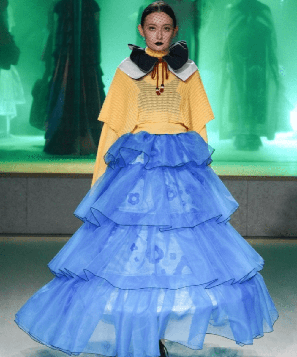 Desfile Nontokyo - saia de tule azul, blusa amarela e gola boneca preta - semana de moda de Tóquio - Inverno  - modelo andando pela passarela - https://stealthelook.com.br