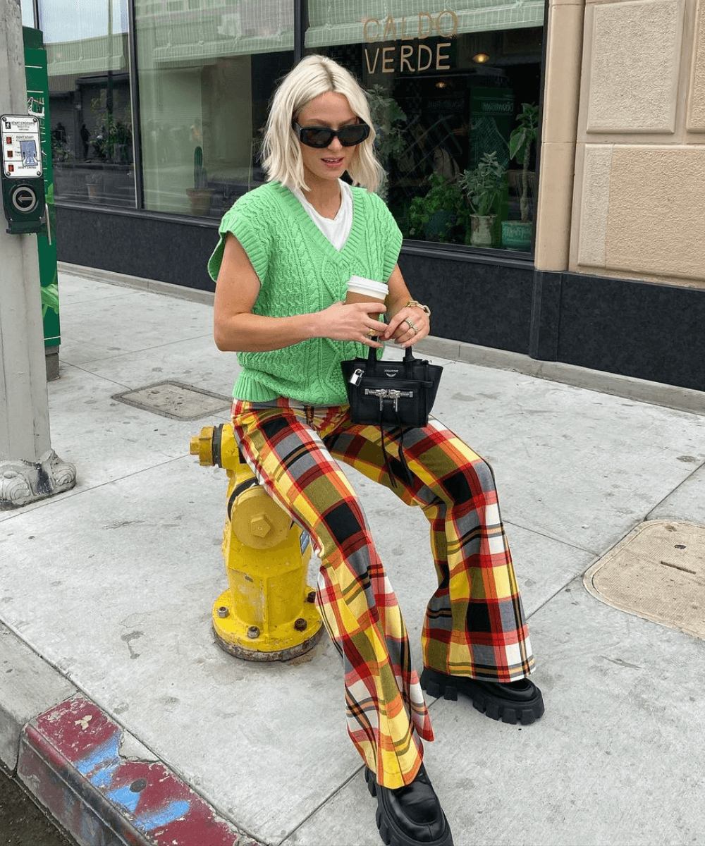 Martha | @marthaeelman - calça xadrez, blusa branca e colete de tricô verde - looks novos - Outono - sentada na rua - https://stealthelook.com.br