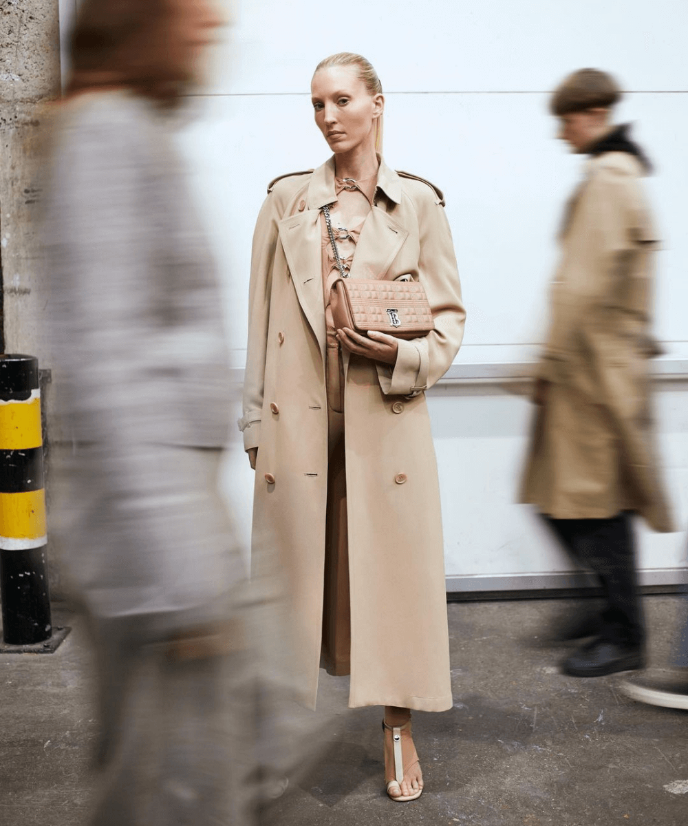 Lola Bag  - trench coat bege e bolsa burberry - lançamentos de moda - Outono - modelo em pé na rua segurando uma bolsa - https://stealthelook.com.br