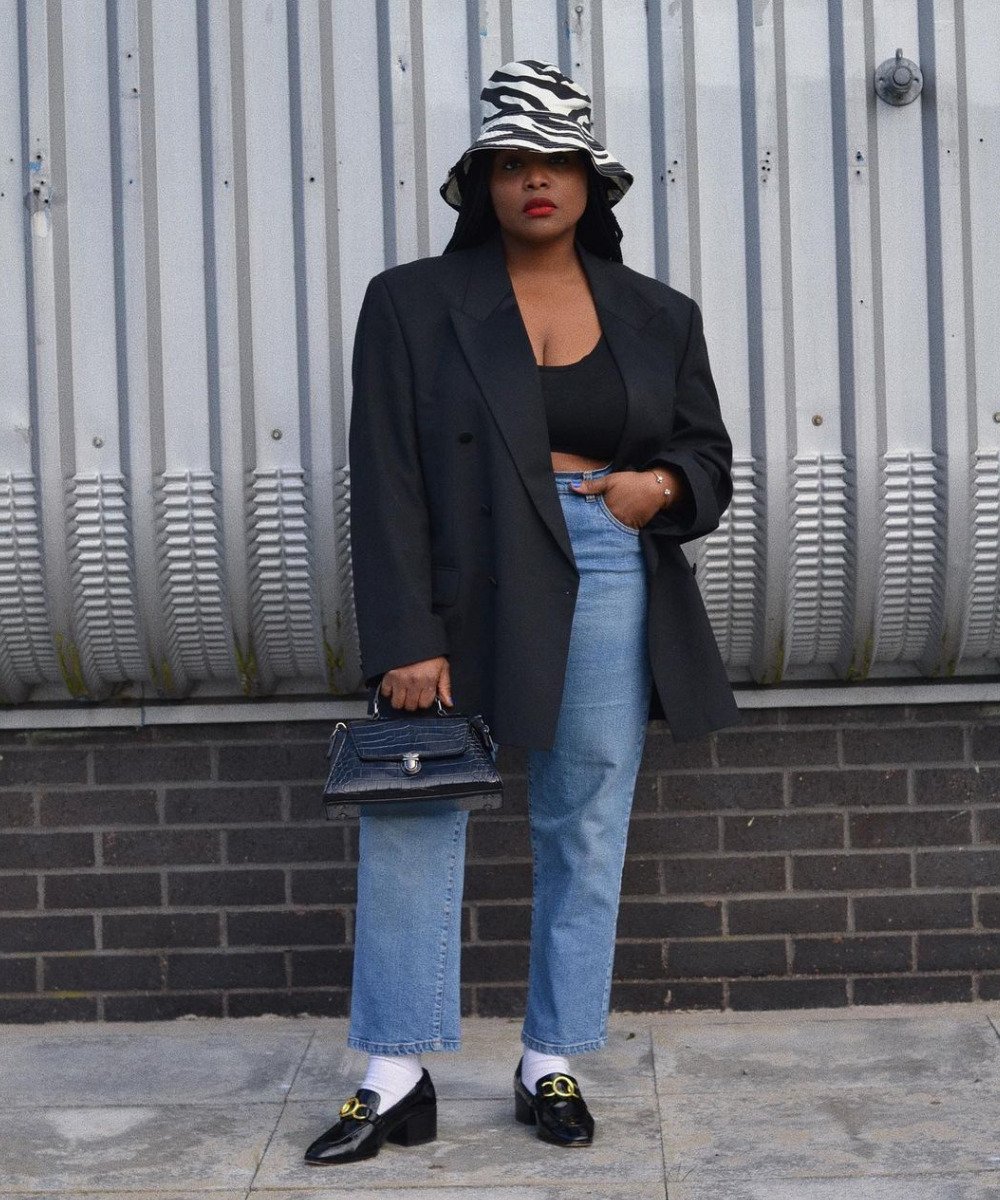 Ada Oguntodu - calça jeans, mocassim, meia, top preto e blazer - outono 2022 - Outono - em pé na rua usando um bucket hat preto e branco - https://stealthelook.com.br