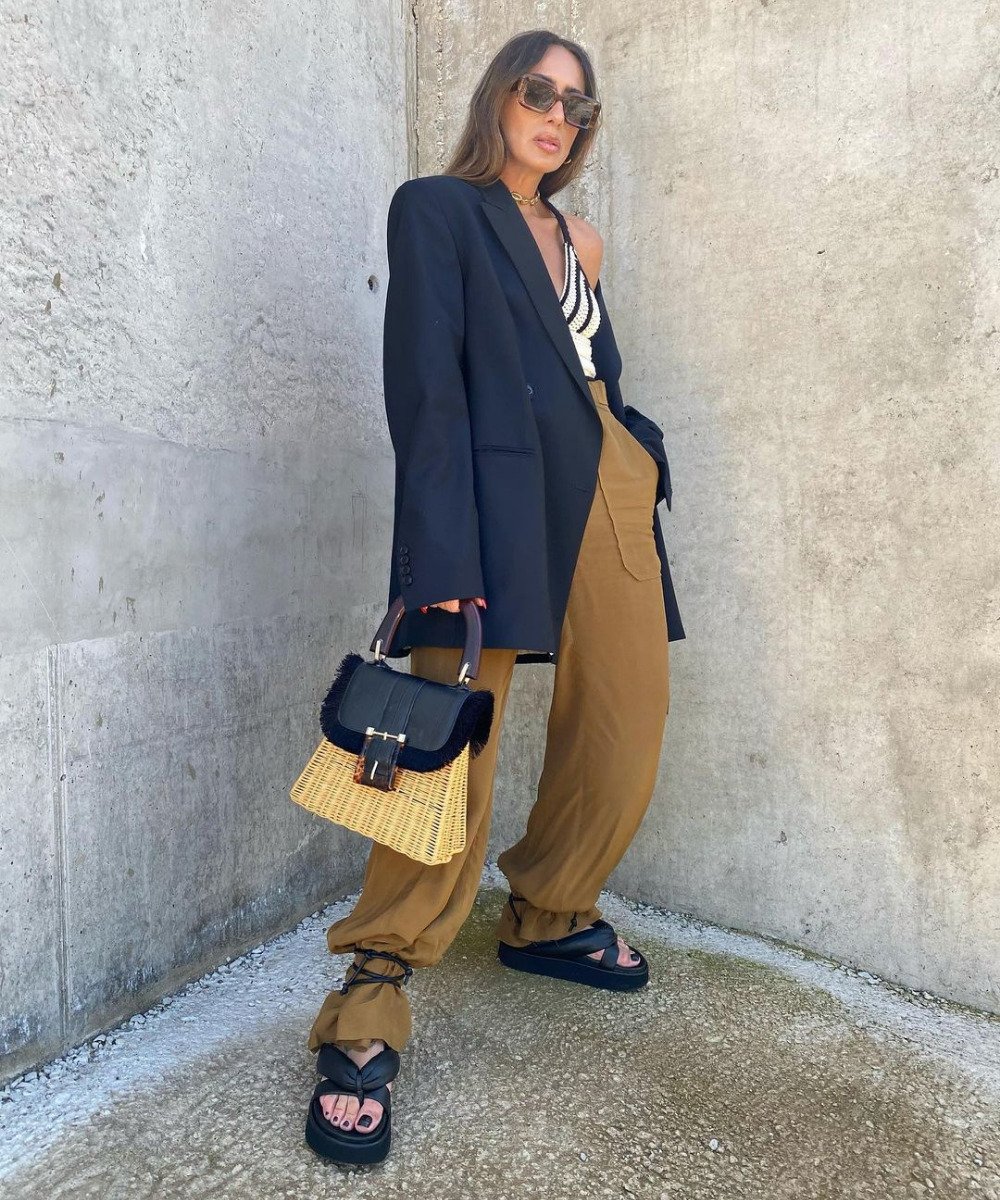 Laura Eguizabal - calça marrom oversized, papete preta, blazer e óculos de sol - outono 2022 - Outono - em pé na rua - https://stealthelook.com.br