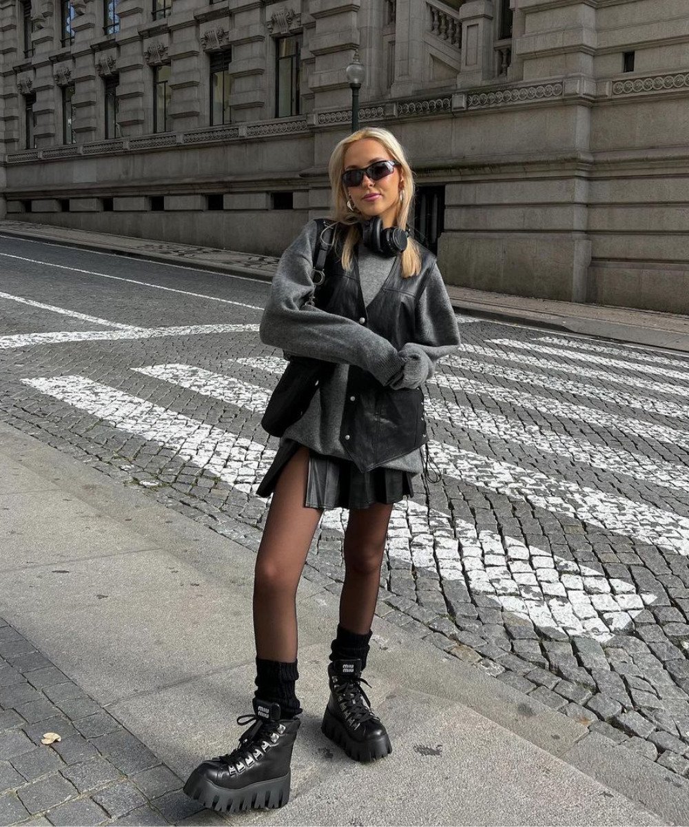 Sofia Coelho - saia preta, moletom cinza, meia-calça e polainas pretas - looks com coturno - Inverno  - em pé na rua usando óculos de sol - https://stealthelook.com.br
