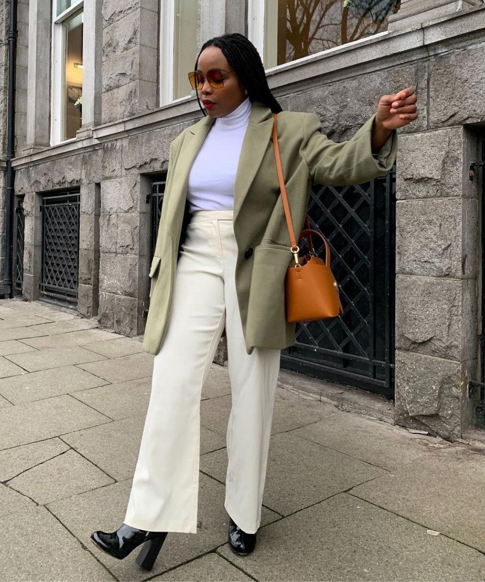 Ada Oguntodu - calça branca, botas, blusa de gola alta e blazer - entrevista de emprego - Outono - em pé na rua usando óculos de sol - https://stealthelook.com.br