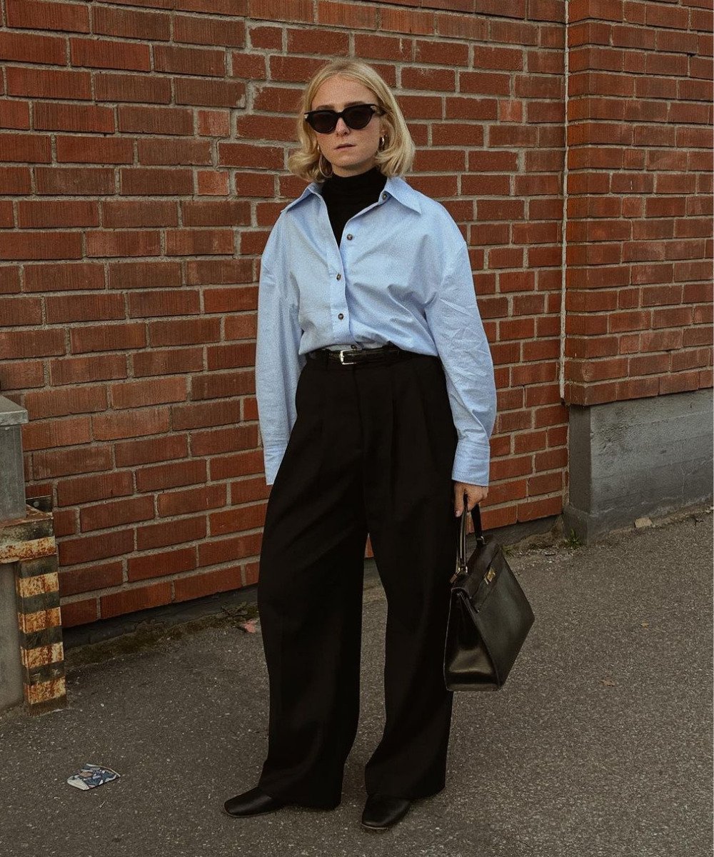 Fanny Ekstrand Tourneur - calça preta, blusa de gola alta preta e camisa azul fechada por cima - entrevista de emprego - Inverno  - em pé na rua usando óculos de sol - https://stealthelook.com.br