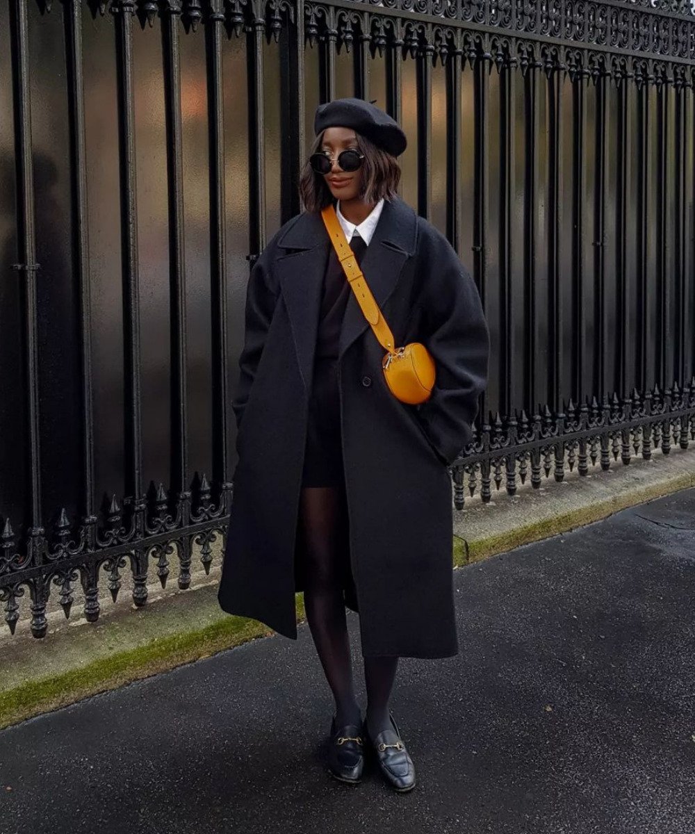 Aïda Badji Sané - meia-calça preta, saia, sobretudo, boina e mules - cores neutras - Inverno - em pé na rua - https://stealthelook.com.br