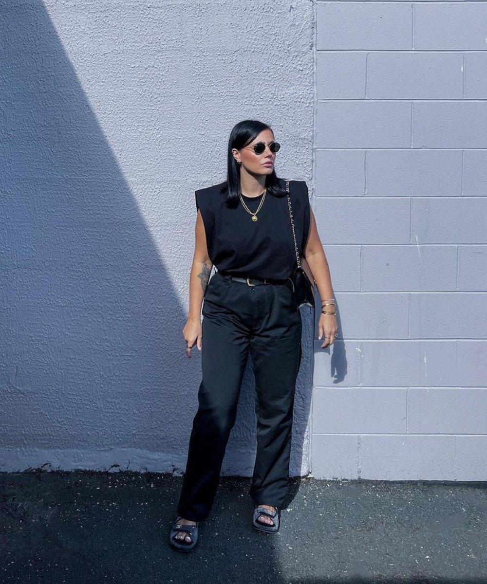 Grace Surguy - calça preta, muscle tee preta e botas - cores neutras - Verão - em pé na rua usando óculos de sol - https://stealthelook.com.br