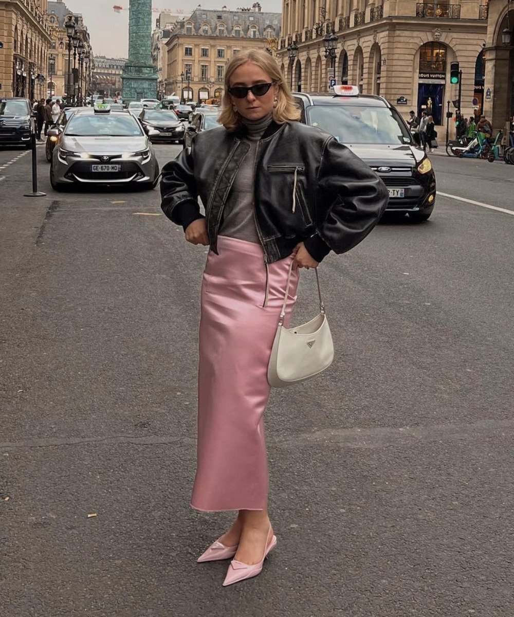 Fanny Ekstrand Tourneur - saia midi acetinada rosa, blusa de gola alta cinza e jaqueta de couro estonada - inverno 2022 - Inverno  - em pé na rua usando óculos de sol - https://stealthelook.com.br