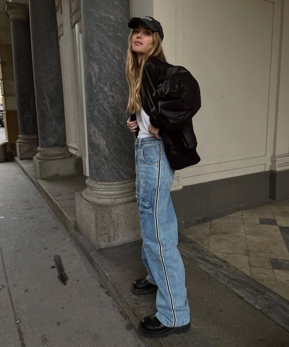 Pernille Teisbaek - calça jeans lookse, bota preta, regata branca e jaqueta de couro preta - inverno 2022 - Inverno  - em pé na rua usando um boné preto - https://stealthelook.com.br