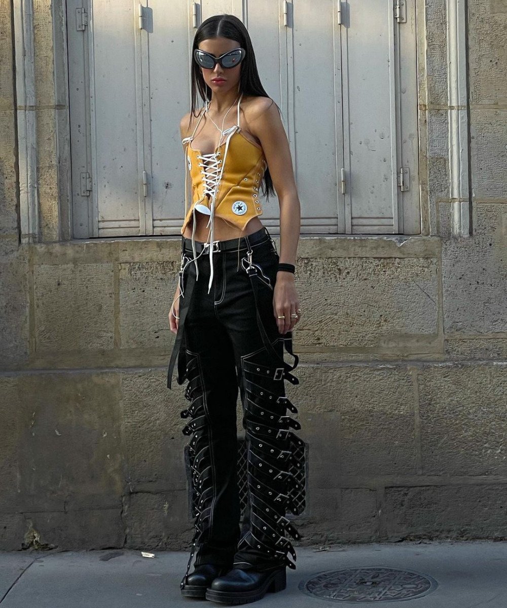 Lívia Nunes Marques - corset de tênis amarelo, calça preta e botas - corsets de tênis - verão - em pé na rua usando óculos de sol - https://stealthelook.com.br