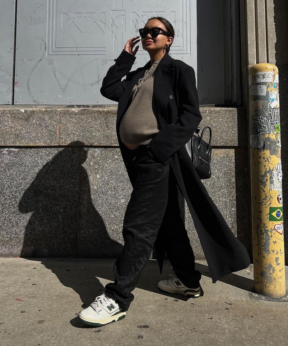 Linh Niller - calça preta, tricô, casaco preto e tênis new balance 550 - tênis da moda - Inverno  - em pé na rua - https://stealthelook.com.br
