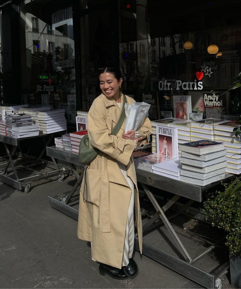 Sasha Mei - vestido de tricot bege, trench coat e coturno preto - tendências de inverno - Inverno  - em pé na rua segurando livros e sorrindo - https://stealthelook.com.br