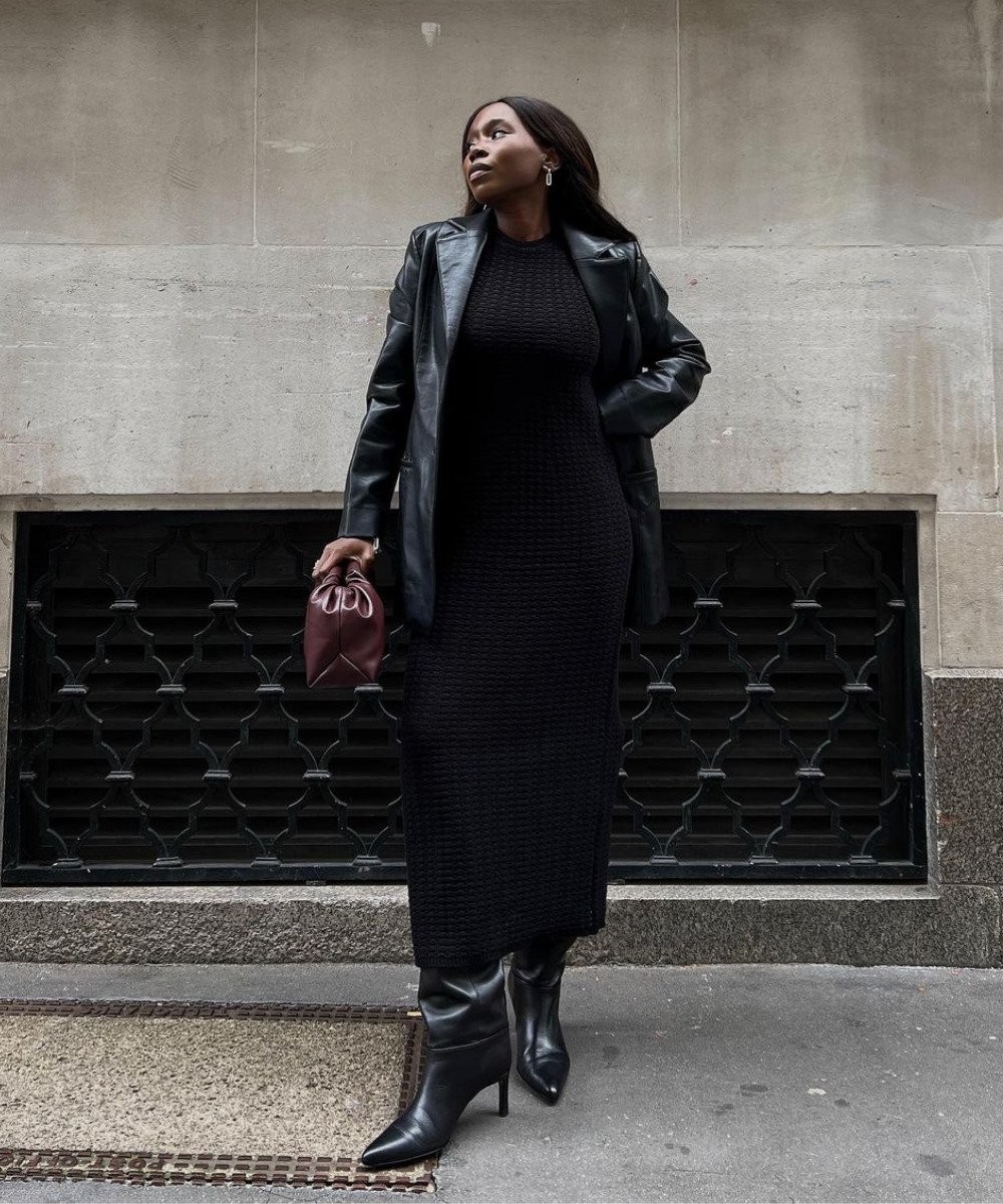 Danielle Jinadu - vestido preto canelado, bota e jaqueta de couro preta - vestidos de inverno - Inverno  - em pé na rua olhando para o lado - https://stealthelook.com.br