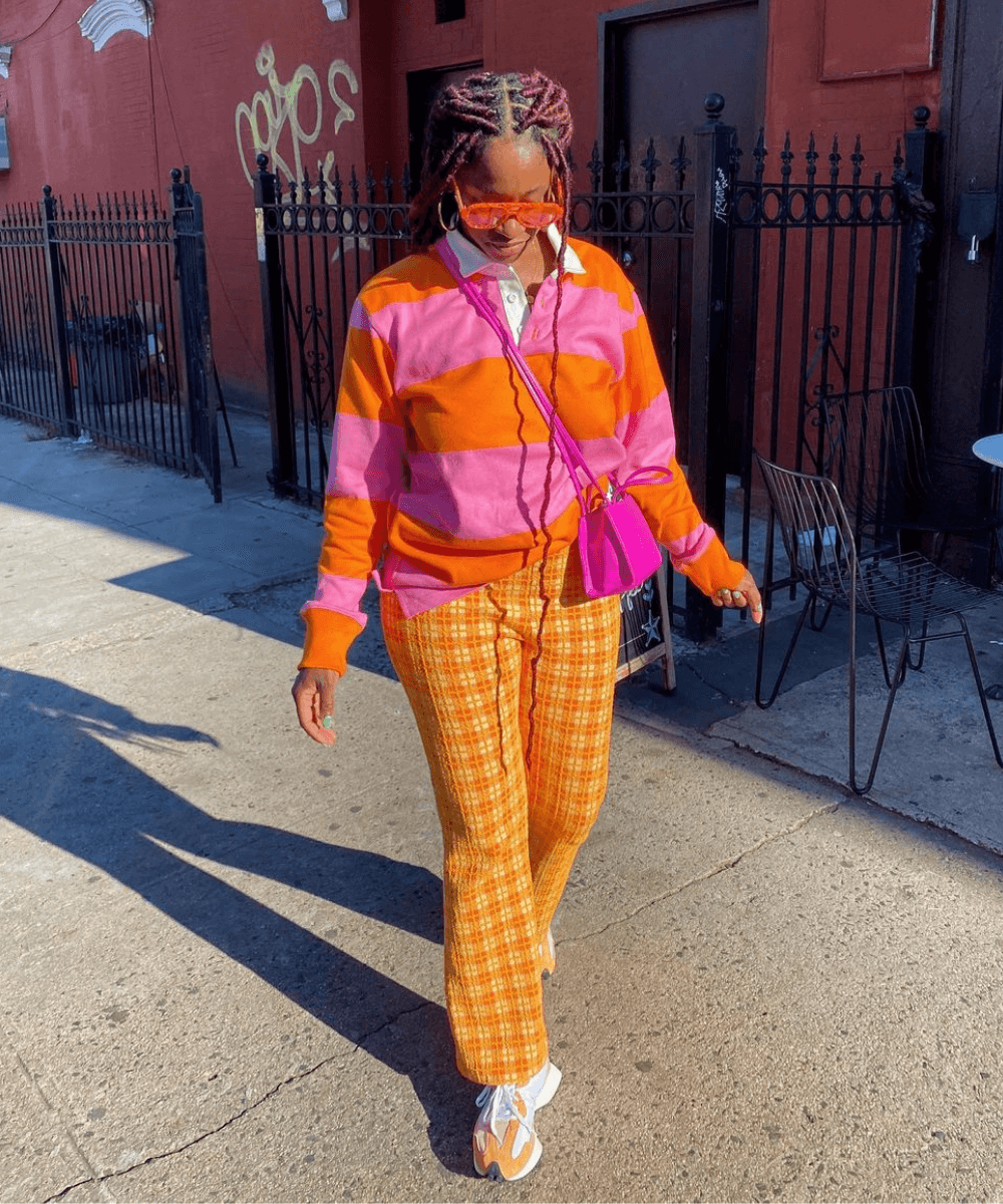 Yolande Macon - calça xadrez laranja, blusa de manga comprida listrada rosa e óculos - looks novos - Inverno  - em pé na rua - https://stealthelook.com.br