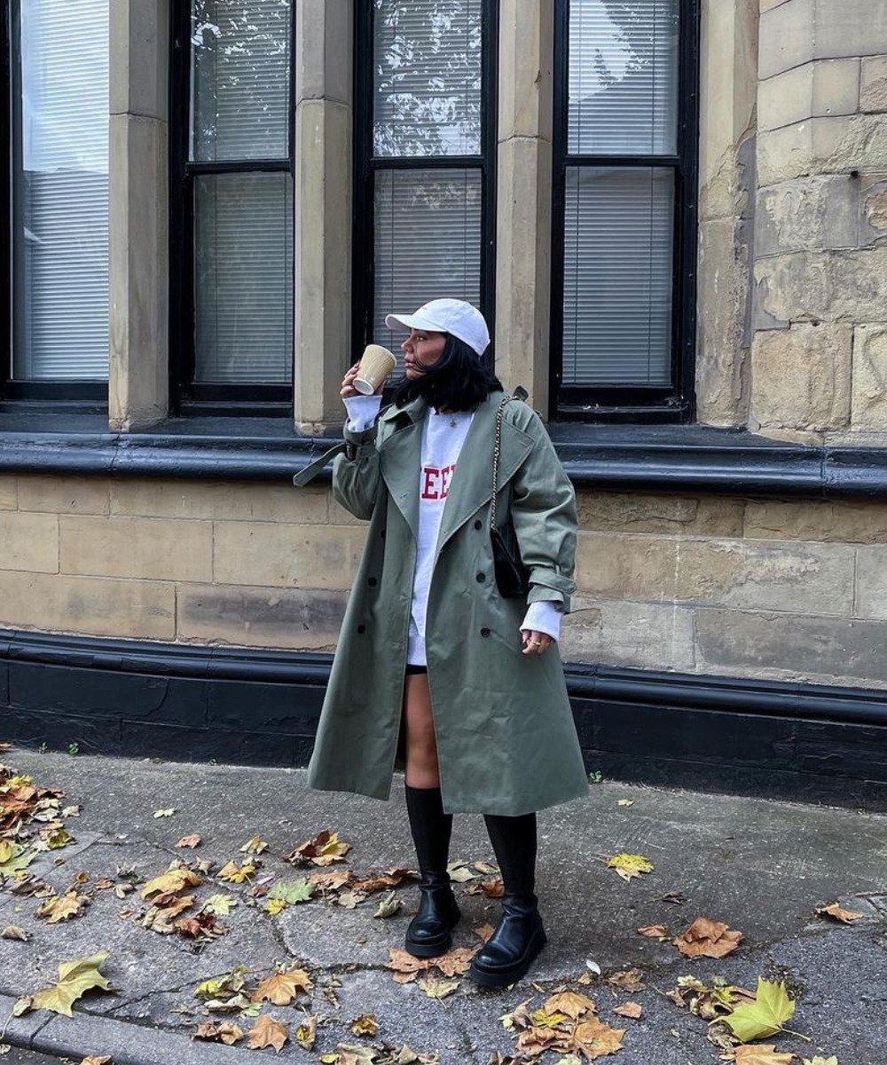 Grace Surguy - trench coat verde, moletom cinza, boné e botas - bota de chuva - Outono - em pé na rua olhando para o lado - https://stealthelook.com.br