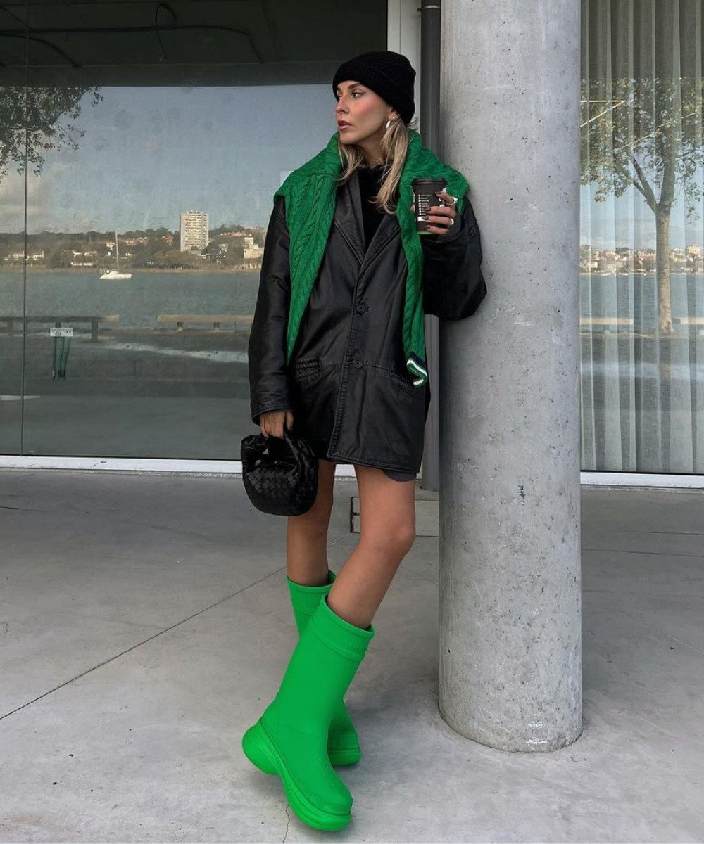 Sofia Coelho - casaco preto, bota de chuva verde e cachecol - bota de chuva - Outono - em pé na rua encostada em uma parede - https://stealthelook.com.br