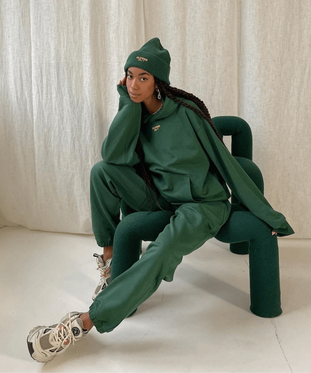 Amaka Hamelijnck - calça de moletom e moletom verde - casacos de inverno - Inverno  - sentada em uma cadeira usando um gorro verde - https://stealthelook.com.br