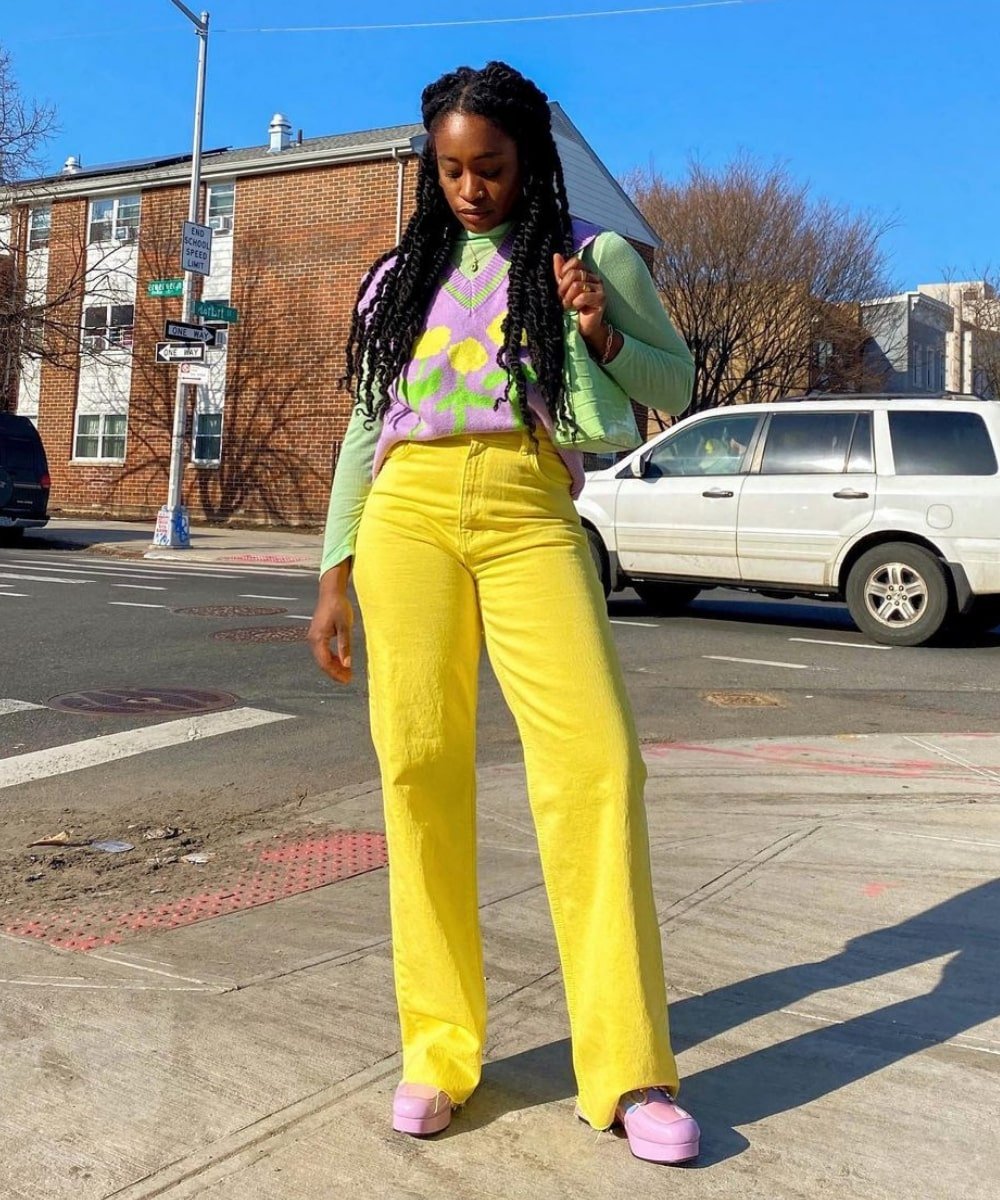 Yolande Macon - calça amarela, blusa de manga longa verde e colete de tricô estampado lilás - inverno 2022 - Inverno  - em pé na rua - https://stealthelook.com.br
