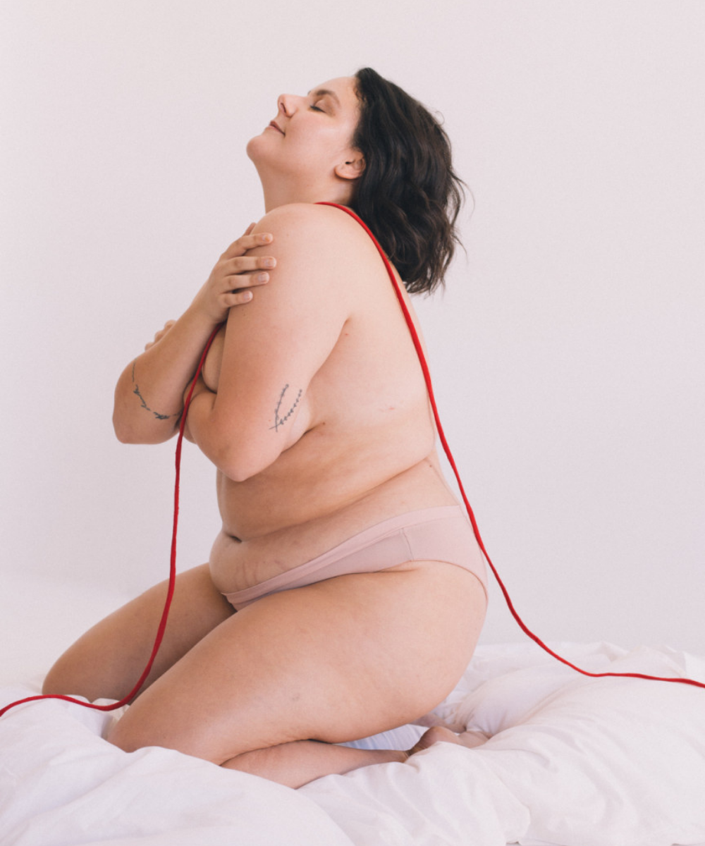 Herself - calcinha bege - Dia Internacional da Higiene Menstrual - Inverno  - mulher de lado em uma cama branca - https://stealthelook.com.br