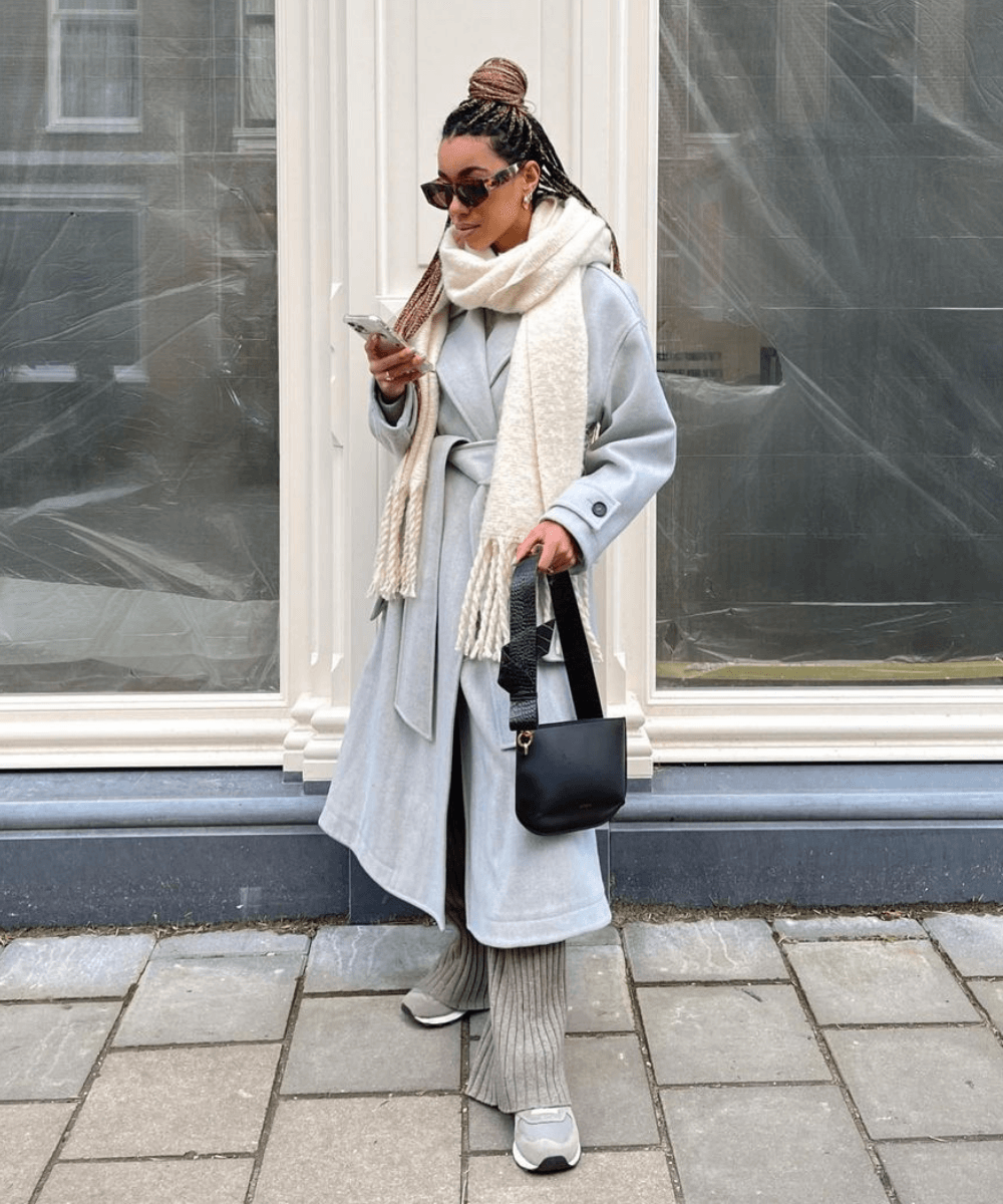 Amaka Hamelijnck - casaco de lã batida, calça, tênis e cachecol - looks de inverno - Inverno  - em pé na rua mexendo no celular - https://stealthelook.com.br