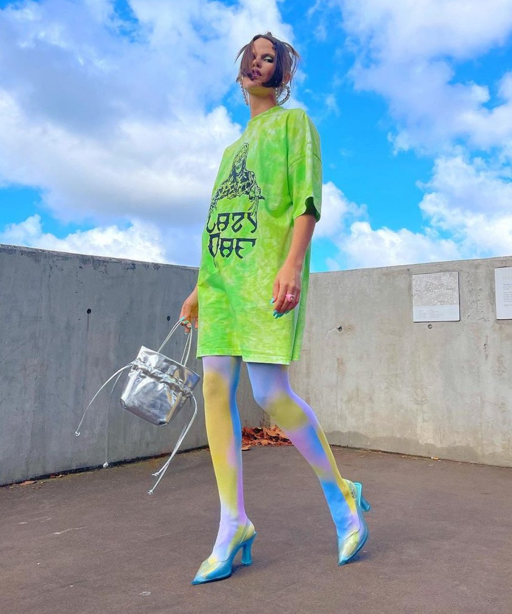 Millie Sykes - vestido verde neon, meia-calça colorida e salto azul - maximalismo meta - verão - em pé na rua - https://stealthelook.com.br