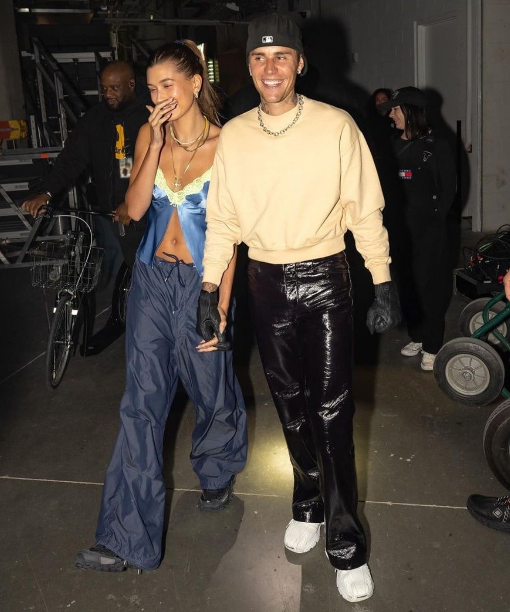 Justin e Hailey Bieber - calça azul, top slip dress e tênis - Hailey e Justin Bieber - Verão - andando juntos de mãos dadas e sorrindo - https://stealthelook.com.br