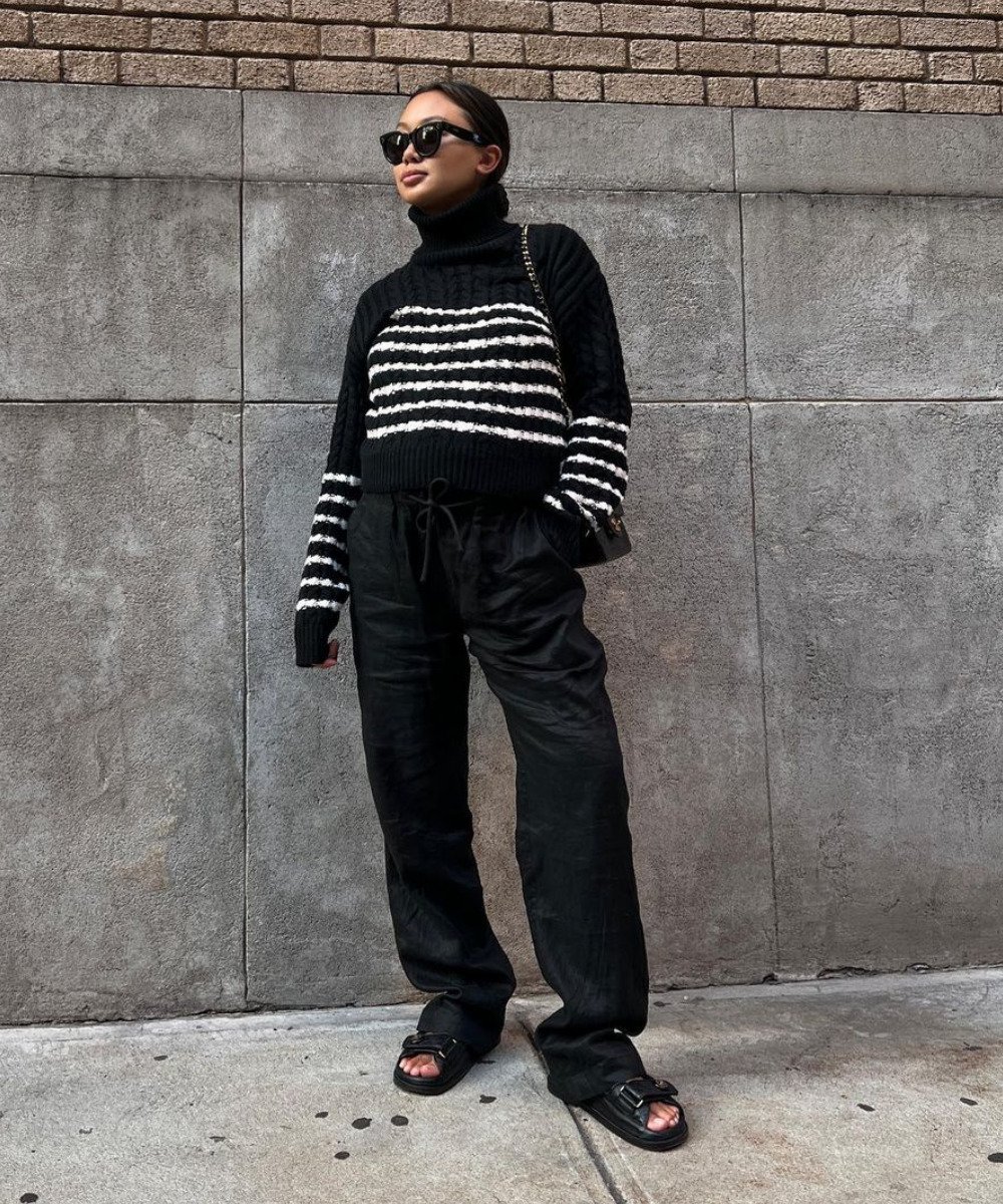 Linh Niller - calça preta, papetes e tricô preto e branco - inverno 2022 - Inverno  - em pé na rua usando óculos de sol - https://stealthelook.com.br