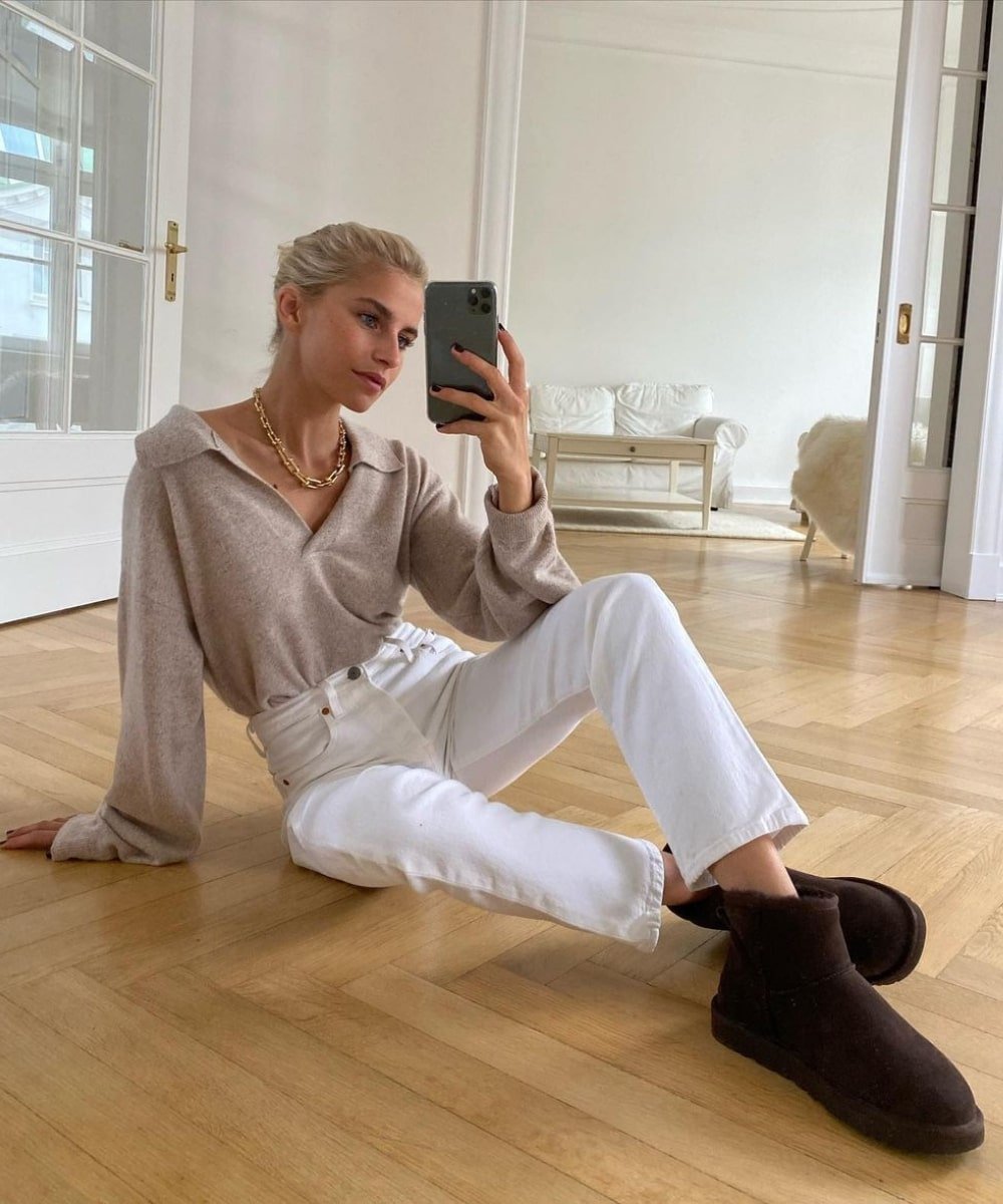 Caroline Daur - calça branca, uggs e tricô de gola polo - looks com bota ugg - Outono - sentada no chão tirando foto no espelho - https://stealthelook.com.br