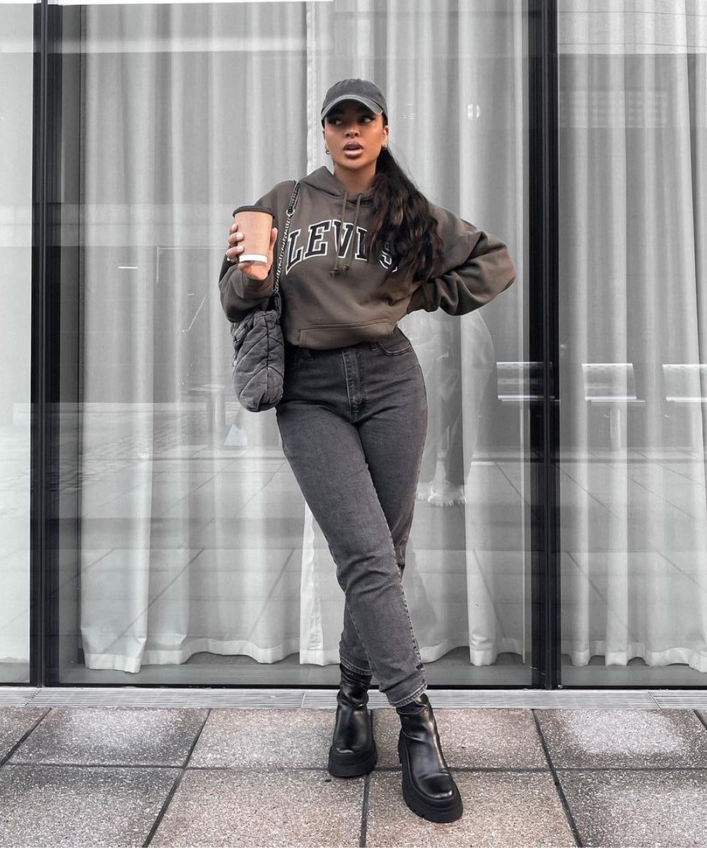 Vanessa Daniels - calça jeans, moletom marrom, boné e botas - looks com moletom - Outono - em pé na rua - https://stealthelook.com.br
